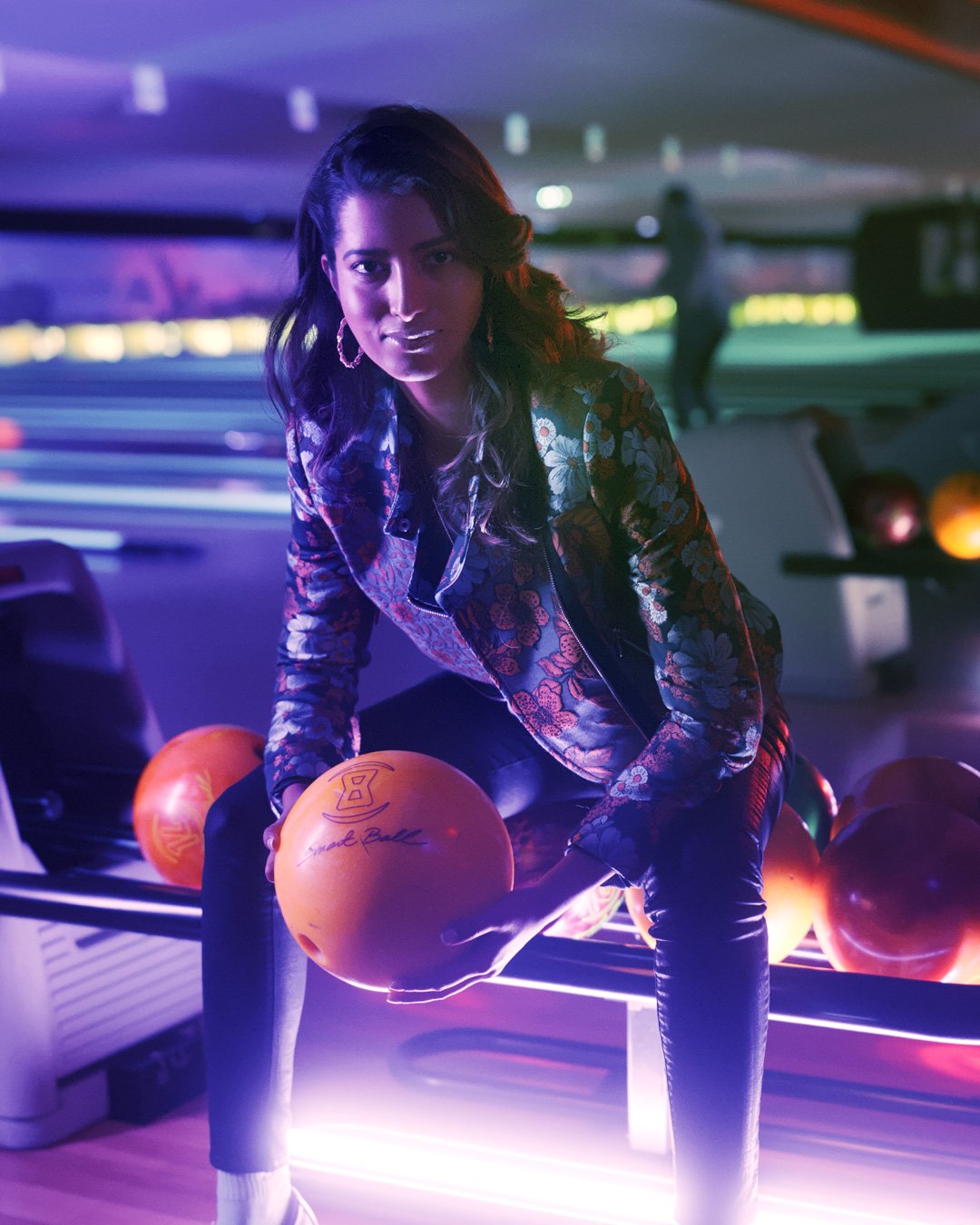 A woman in the Motorola One Zoom launch campaign, lit by purple and blue arcade lights.