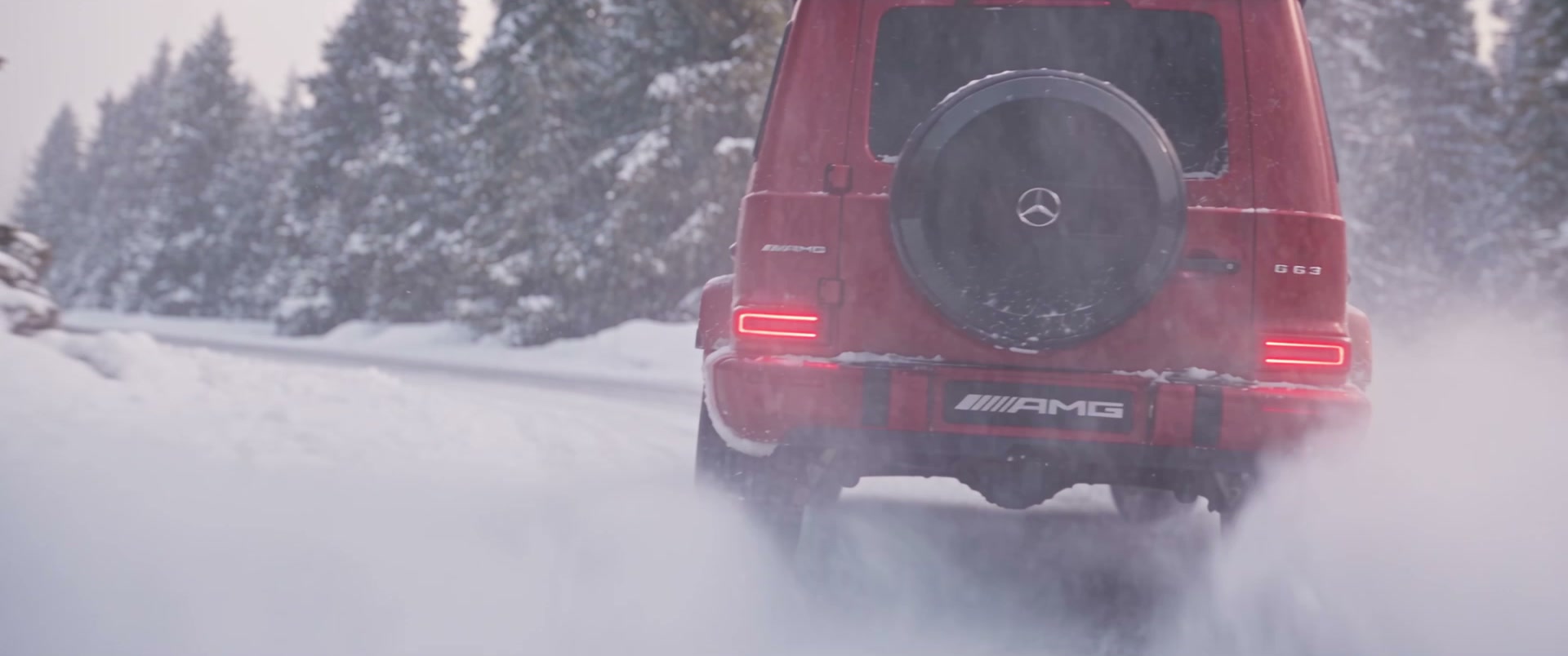 Rear tracking view of the G-Class driving away through trailing powder snow